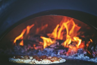 Image of a pepperoni pizza in a wood fired oven