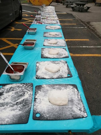 Table full of dough balls awaiting to be turned in pizzas for a school lesson